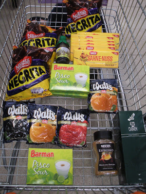 Looking down into grocery cart with Watts barnd jam, sahne-nuss chocolate, bags of chocolates, coffe, and pisco