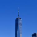 Top half of the Freedom Tower, One World Trade Center and blue sky background.