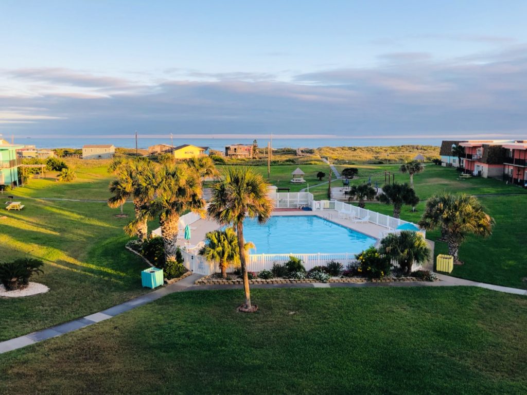 View of the ocean in Port Aransas. You can see the grass and pool area and Texas coastline in the background.