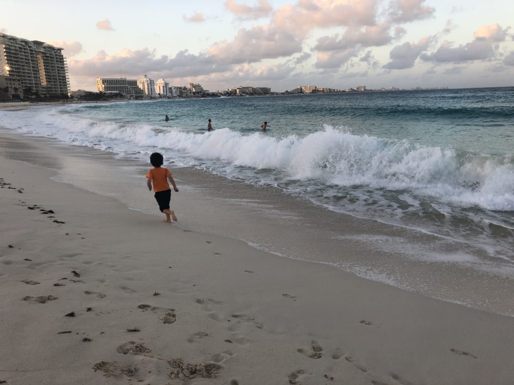 boy running on the beach in cancun mexico at sunset
