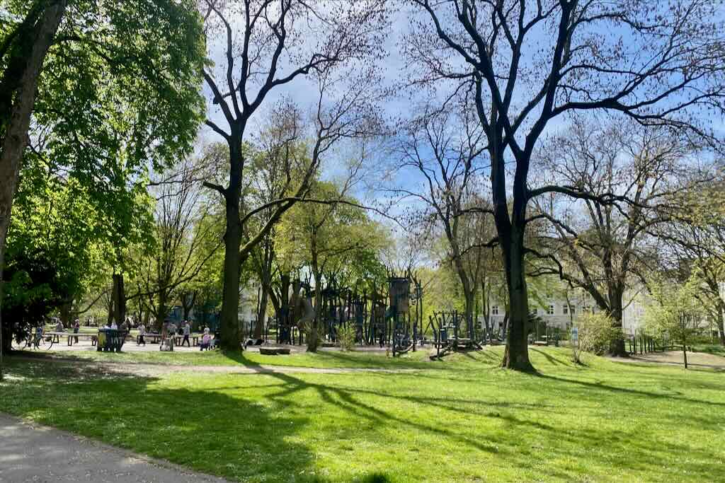 west park in dortmund in the spring with bright green grass in foreground and playground and picnic benches in background